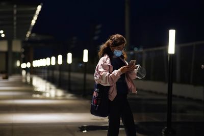 Full length of woman with illuminated lights at night