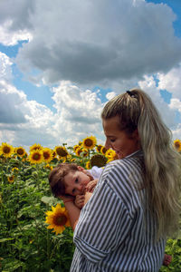 Mother and son standing by flower against sky