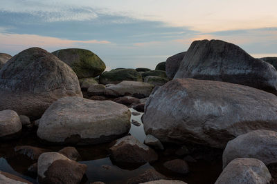 Rocks on beach against sky during sunset