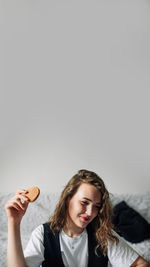 Portrait of smiling young woman holding apple against white background