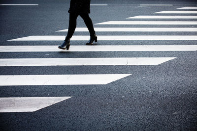 Low section of woman walking on zebra crossing