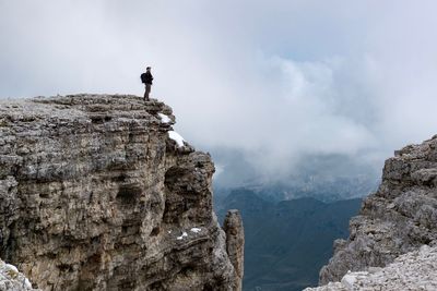 Man standing on cliff against sky