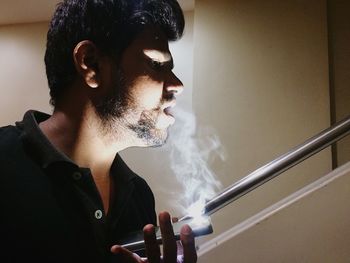 Close-up of man smoking against wall
