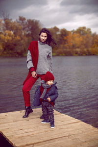 Woman in a sweater with a child standing on a bridge cold autumn on the river