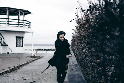 Portrait of young woman standing against sky