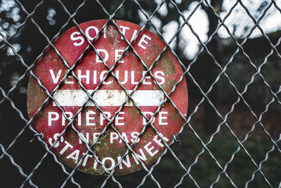 Close-up of red sign on chainlink fence