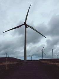 Windmill on field against cloudy sky