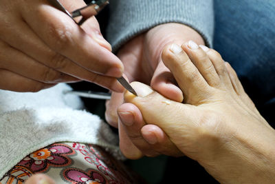 Close-up of beautician cleaning customer nails