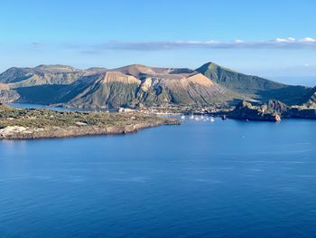 Scenic view of sea and mountains against blue sky