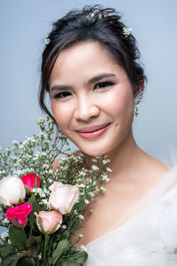 Portrait of happy woman with flower bouquet against plants