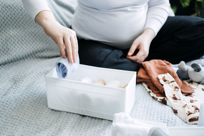 How to organize newborn baby clothes. pregnant woman using ornament boxes, baskets, or dividers to