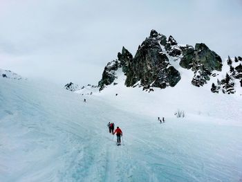 People skiing on snowcapped mountain against sky