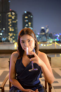 Portrait of beautiful young woman with wineglass sitting on terrace 