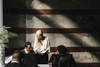 Female financial advisor discussing over document with colleagues at law office