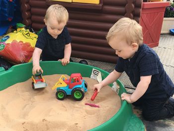 Cute twins brothers playing with toys on sandbox in preschool