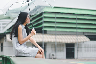 Woman holding umbrella while sitting in rain