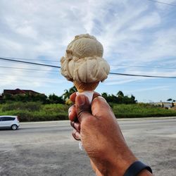 Hand holding umbrella ice cream cone by the street