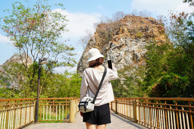 Rear view of man standing on railing against mountain