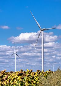 Wind generators in a sunflower field against a cloudy sky  in ukraine on a sunny summer day