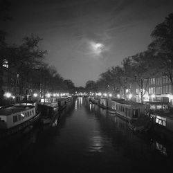 Boats moored on illuminated city at night