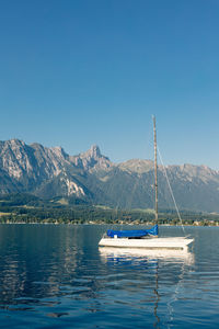 Sailboats in lake against clear blue sky