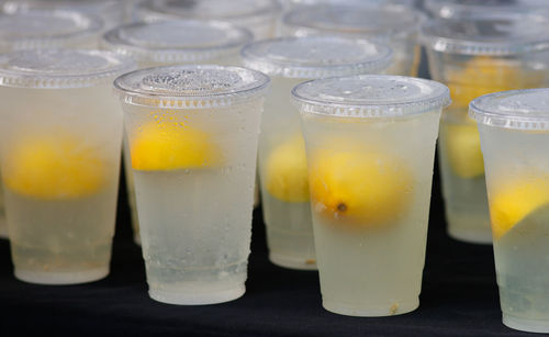 Close-up of plastic cups of water with lemons 