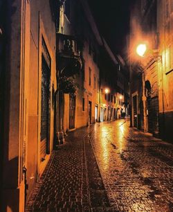 Illuminated street amidst buildings at night