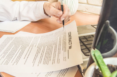 Midsection of woman reading book on table