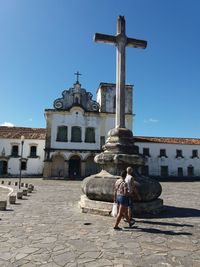 Man on cross against building against clear sky