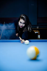 Portrait of young woman playing pool