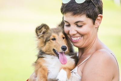Smiling woman carrying dog in park