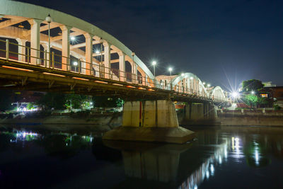 Bridge over river in city against sky at night