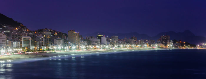 City by sea against sky at night