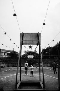 Rear view of people playing against clear sky