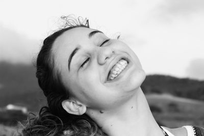 Close-up of smiling young woman against sky