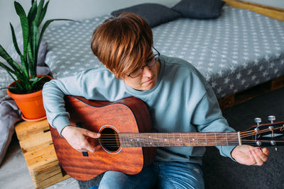 Woman with short hair enjoys playing guitar at home. music lessons for adults
