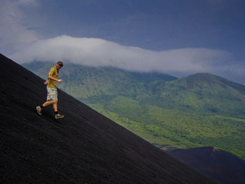 Man walking on mountain against sky