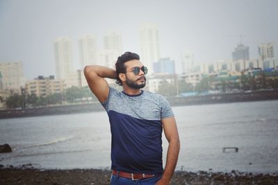 Man wearing sunglasses while standing against lake in city