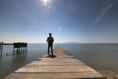 Man standing on pier over sea against sky