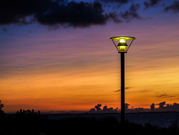 Street light against cloudy sky during sunset