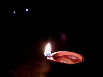 Close-up of lit candle in darkroom