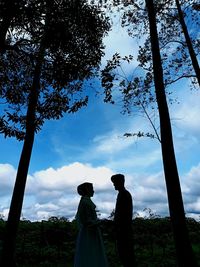 Silhouette people standing by tree against sky