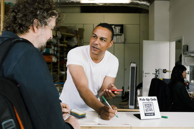 Repairman writing down details of customer at store