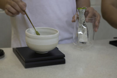 Midsection of woman drinking glass on table