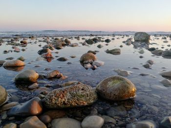 Rocks on beach against sky during sunset