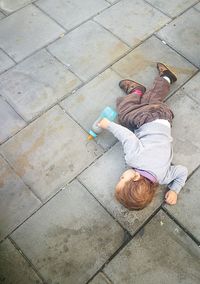 High angle view of baby boy with bottle lying on footpath