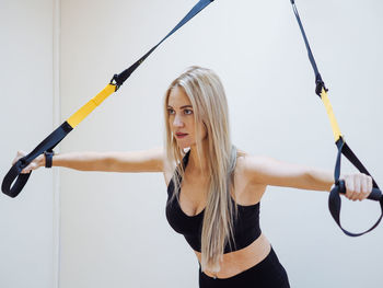 Portrait of young woman exercising on field