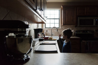 Boy looking at waffle on tray while standing in kitchen