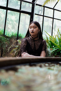 Portrait of young woman looking through window