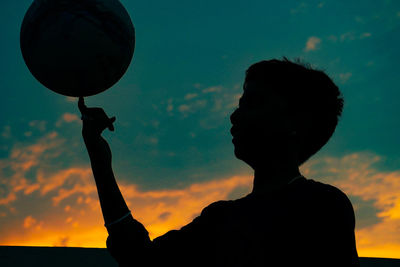 Low angle view of silhouette man holding orange sky during sunset